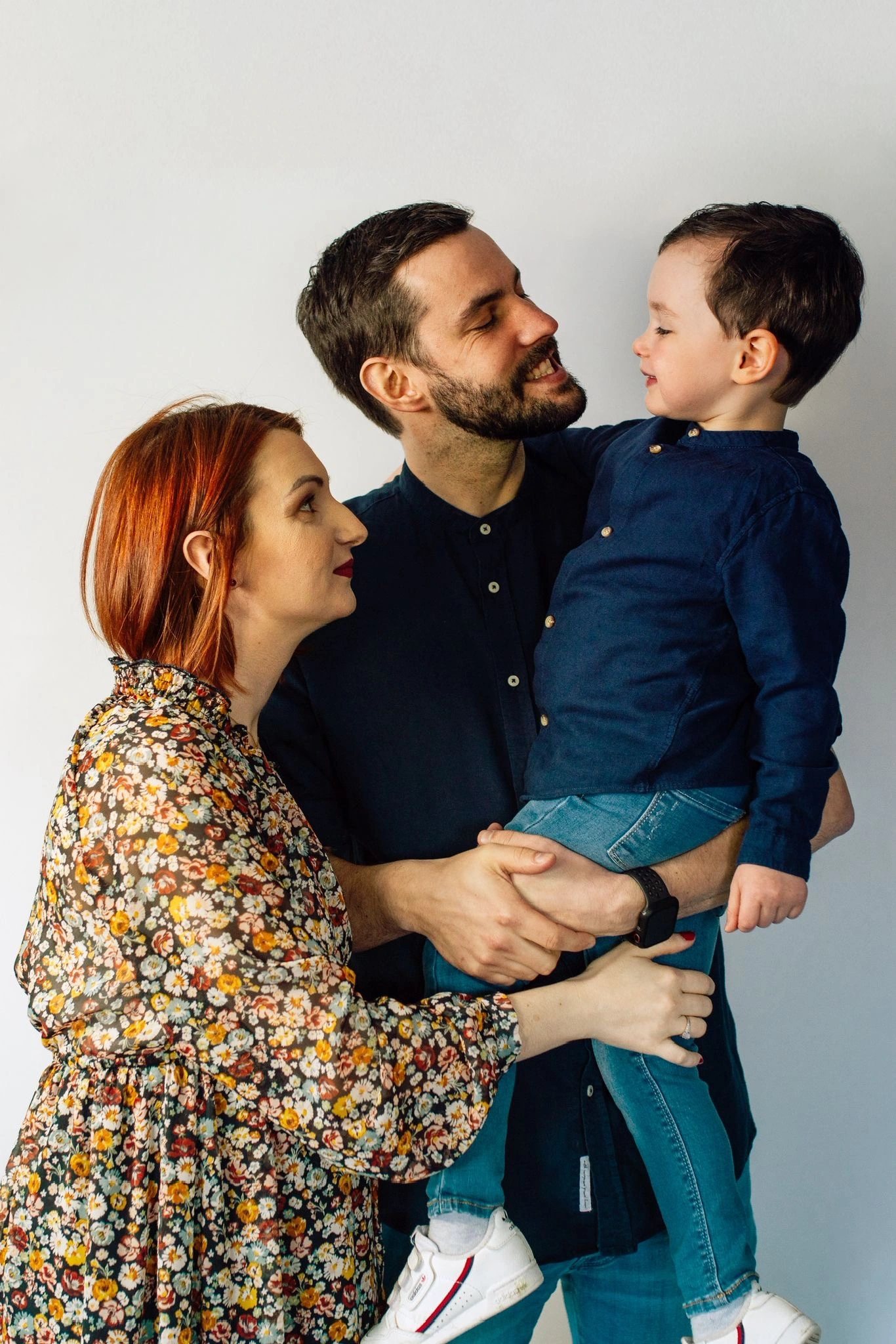 Un couple souriant tenant leur jeune enfant dans les bras, complicité et tendress
